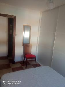 una camera da letto con sedia rossa e specchio di Apartamento grumete a El Puerto de Santa María