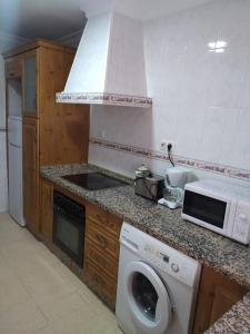 una cucina con lavatrice e microonde di Apartamento grumete a El Puerto de Santa María Altre 4 foto