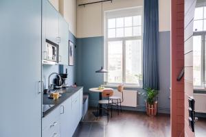 a kitchen with blue walls and a table and chairs at Forenom Aparthotel Malmö Varvsstaden in Malmö