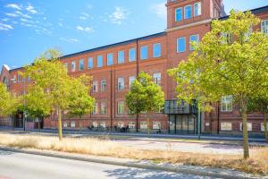 un gran edificio de ladrillo con árboles delante de él en Forenom Aparthotel Malmö Varvsstaden, en Malmö