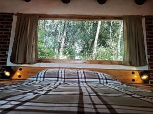 ein Schlafzimmer mit einem Bett und einem großen Fenster in der Unterkunft Cabaña para pareja en el bosque IB in Acaxochitlán