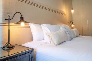 a bed with white pillows and a table with a lamp at Silver Run Thredbo in Thredbo