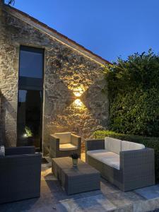 un patio con sofás, mesas y una pared de piedra. en Maison de village avec terrain et piscine dans le Parc Régional du Haut Languedoc, en Le Pradal