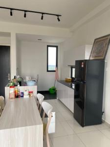 uma cozinha com uma mesa e um frigorífico preto em Eco Nest 3 Bedroom Duplex Apartment em Nusajaya