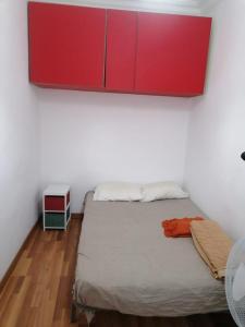 Apartamento con encanto Mila VALENCIAYOLE في فالنسيا: غرفة نوم مع سرير مع خزانة حمراء فوقها