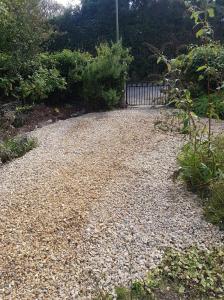 a gravel driveway with a fence in a garden at The Old Sunday School in Helston