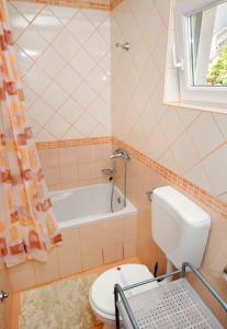 La salle de bains est pourvue de toilettes et d'une baignoire. dans l'établissement Apartments and rooms with parking space Senj - 5569, à Senj
