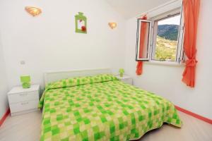 a bedroom with a green and white bed and a window at Apartments with a parking space Bol, Brac - 5642 in Bol