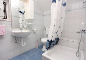 a bathroom with a sink and a toilet and a shower curtain at Apartments by the sea Splitska, Brac - 5664 in Splitska