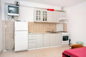 a kitchen with white cabinets and a tv on the wall at Apartments by the sea Cove Solotisa, Hvar - 5610 in Bogomolje