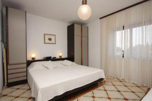 a bedroom with a white bed and a large window at Apartments by the sea Sumartin, Brac - 5619 in Sumartin