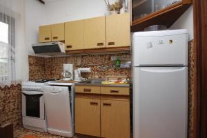 a kitchen with a white refrigerator and wooden cabinets at Apartments by the sea Sumartin, Brac - 5619 in Sumartin +16 photos