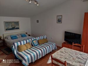 a bedroom with a bed and a couch and a tv at Apartments by the sea Selce, Crikvenica - 5550 in Selce