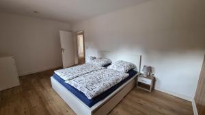 a white bedroom with a bed and a wooden floor at Naturhof Buschwiesen - Wohnung Nandu in Wilsum