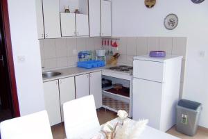 a small kitchen with white cabinets and a white refrigerator at Apartments with parking space Vantacici, Krk - 5566 in Malinska