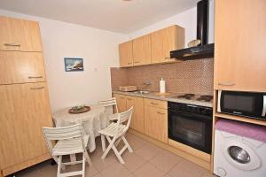 cocina con mesa, sillas y microondas en Apartments with WiFi Supetar, Brac - 5665, en Supetar