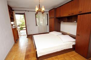 Schlafzimmer mit einem großen weißen Bett und Holzschränken in der Unterkunft Apartments by the sea Sumartin, Brac - 5615 in Sumartin