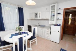 eine Küche mit einem Tisch und Stühlen sowie eine weiße Küche in der Unterkunft Apartments by the sea Sumartin, Brac - 5615 in Sumartin