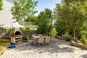a patio with a table with an umbrella and a grill at Apartments by the sea Klenovica, Novi Vinodolski - 5575 in Klenovica