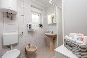 a white bathroom with a toilet and a sink at Apartments by the sea Klenovica, Novi Vinodolski - 5575 in Klenovica