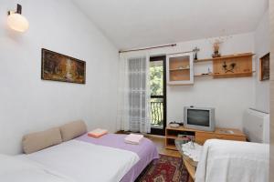 a small room with two beds and a television at Apartments with parking space Supetar, Brac - 5653 in Supetar