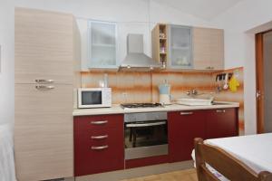 a small kitchen with a microwave and a stove at Apartments with parking space Supetar, Brac - 5653 in Supetar