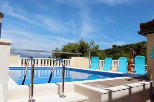 a view of a swimming pool with blue chairs at Family friendly house with a swimming pool Postira, Brac - 5661 in Postira