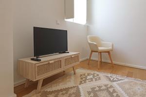 uma sala de estar com uma televisão e uma cadeira em FLH Gaia Homey Studio em Vila Nova de Gaia