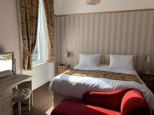 a bedroom with a large bed with a red ottoman in it at The Snowdonia Apartments in Llandudno