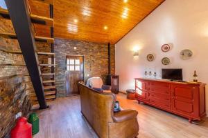 uma sala de estar com uma cadeira de couro e uma parede de tijolos em Casa de São bento - Monsaraz em Monsaraz
