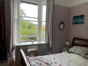 a bedroom with a bed and a desk and a window at Airy Apartment Sefton Park in Liverpool