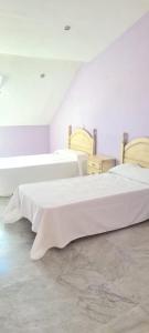 two beds in a room with white walls at Duplex centro Lidia in Ronda