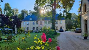 une grande maison avec des fleurs devant elle dans l'établissement Château de Bellefontaine - Teritoria, à Bayeux