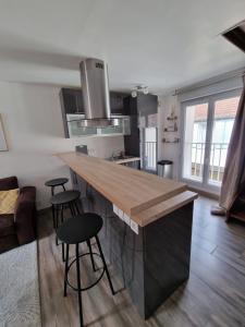 une cuisine avec un comptoir et des tabourets dans une pièce dans l'établissement Duplex 40m2 cocooning cœur de ville avec parking, à Neauphle-le-Château