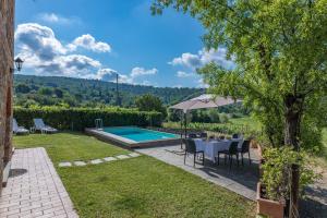 un jardín con mesa, sombrilla y piscina en Villa Poggio alle Case, en Pergine Valdarno