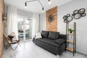 a living room with a black couch and a brick wall at Family Apartment 62m - Sowia with GARAGE & BALCONY by Renters in Poznań