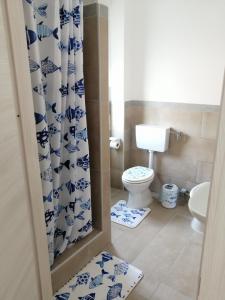 uma casa de banho com um WC e uma cortina de chuveiro azul e branco. em Albergo blue fish em Albisola Superiore