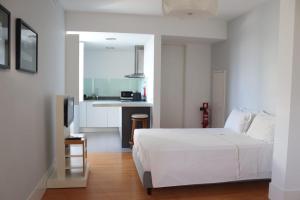 a bedroom with a white bed and a kitchen at Casa do Vidoeiro in Seia