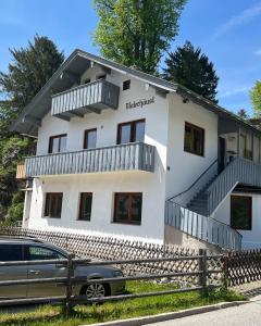 ein weißes Haus mit einem davor geparkt in der Unterkunft Ferienwohnung Kohl - Malerhäusl - Berchtesgaden in Berchtesgaden