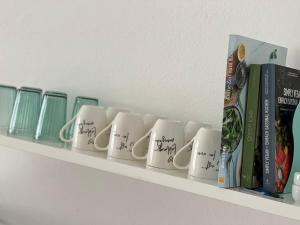 Ein Regal mit einem Haufen Kaffeetassen und Büchern. in der Unterkunft Ferienwohnung Kohl - Malerhäusl - Berchtesgaden in Berchtesgaden