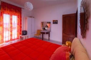 1 dormitorio con cama roja y escritorio en Limoni Sul Mare, en Torre Faro