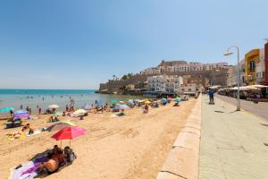 una playa con gente sentada en la arena y el océano en Bungalows Camping el Cid en Peñíscola