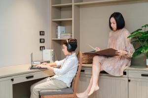 a boy and a girl sitting at a desk with a laptop at THEA Serviced Apartment by TH District, SHA Extra Plus in Bangkok