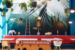 a restaurant with a red couch and a mural of plants at ibis Styles Toulon Centre Port in Toulon