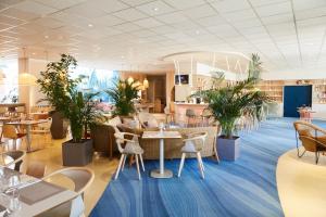 a restaurant with tables and chairs and plants at ibis Styles Toulon Centre Port in Toulon