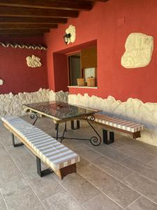 una mesa y bancos frente a una pared roja en Casa Aurora, en Sanchidrián