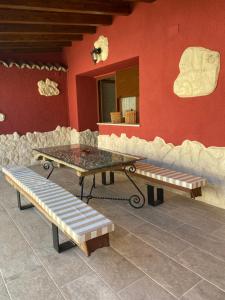 einem Tisch und Bänken vor einer roten Wand in der Unterkunft Casa Aurora in Sanchidrián