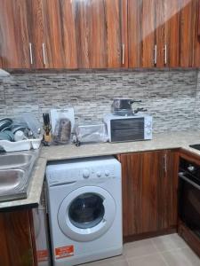 a kitchen with a washing machine and a microwave at Tapis Guest House in Brikama