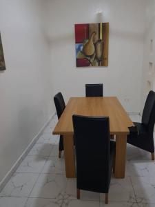 einen Esstisch mit Stühlen und ein Gemälde an der Wand in der Unterkunft Tapis Guest House in Brikama