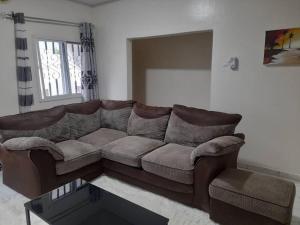 a living room with a brown couch and a table at Tapis Guest House in Brikama